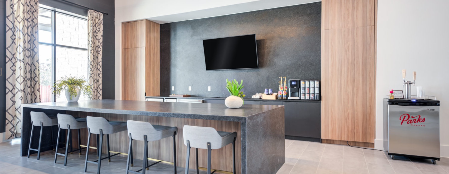 a community kitchen with a bar chairs and tv